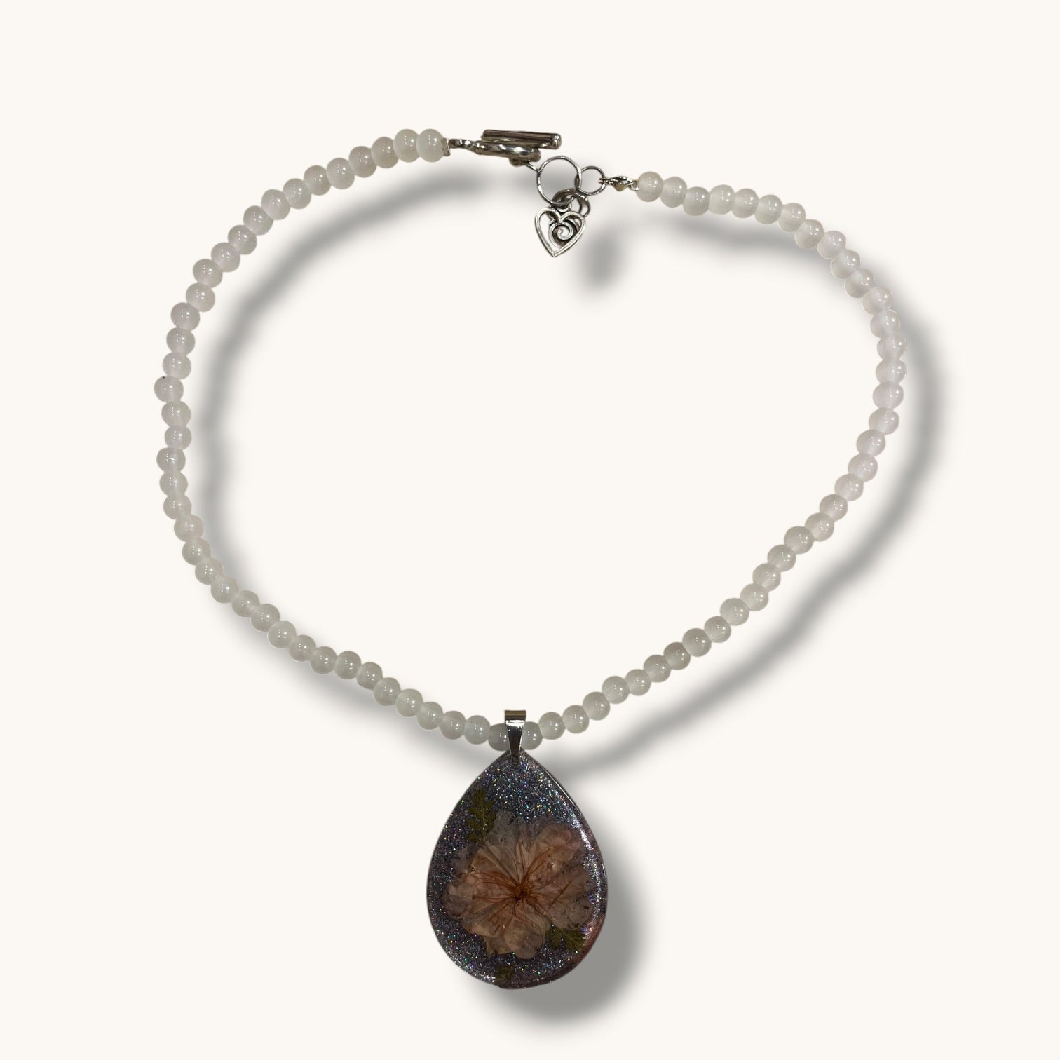 Teardrop resin pendant with a real white daisy flower on a white beaded choker necklace with a silver toggle clasp