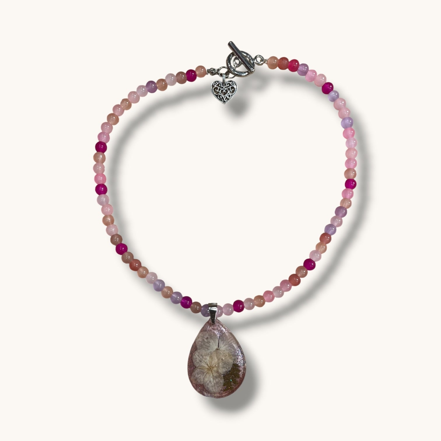 Teardrop resin pendant with a real white daisy flower on a pink beaded choker necklace with a silver toggle clasp